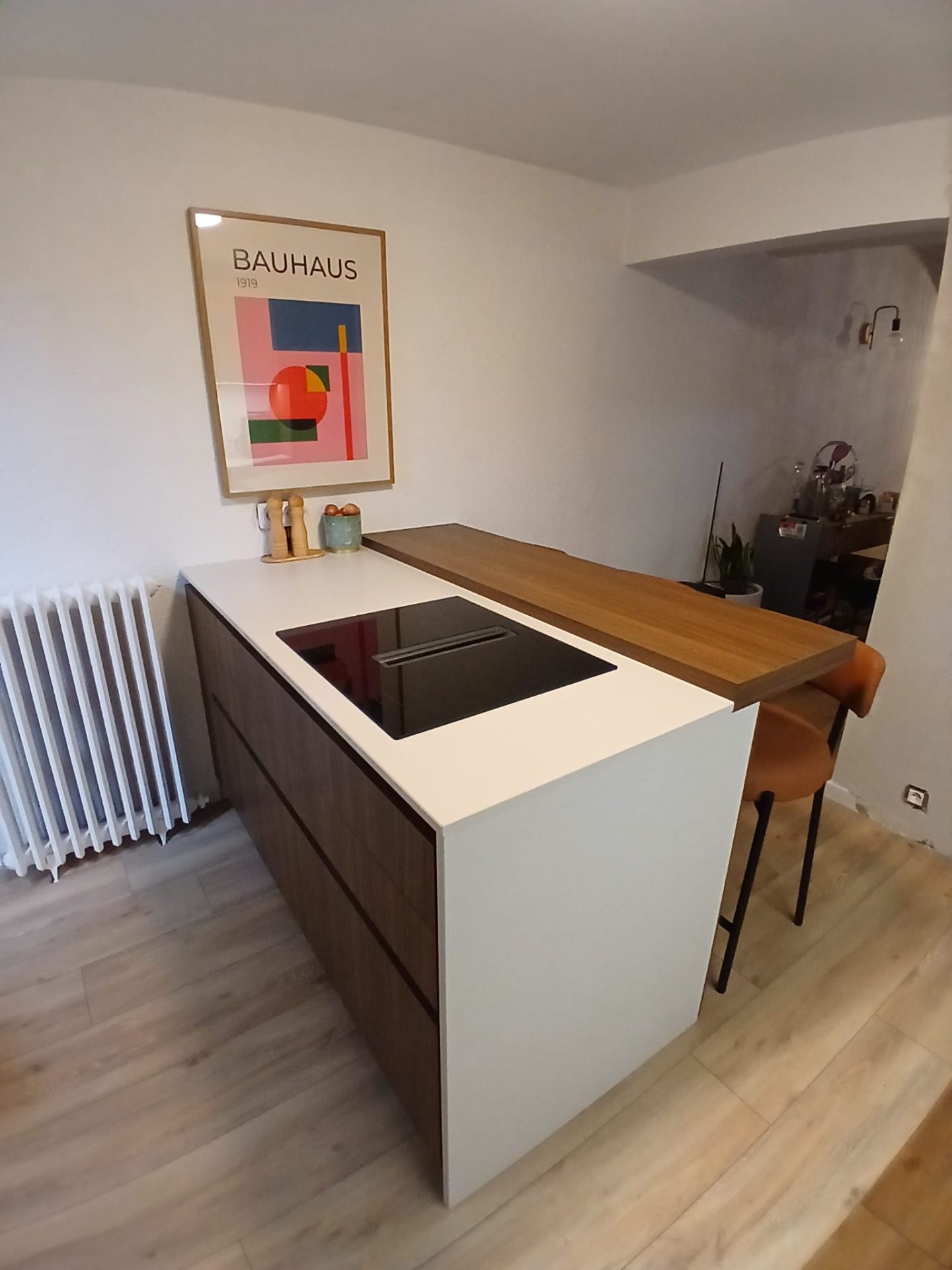 Installation d'une cuisine épurée comprenant un îlot blanc avec table en bois intégrée par NA Concept, concepteur à Mauléon-Licharre.