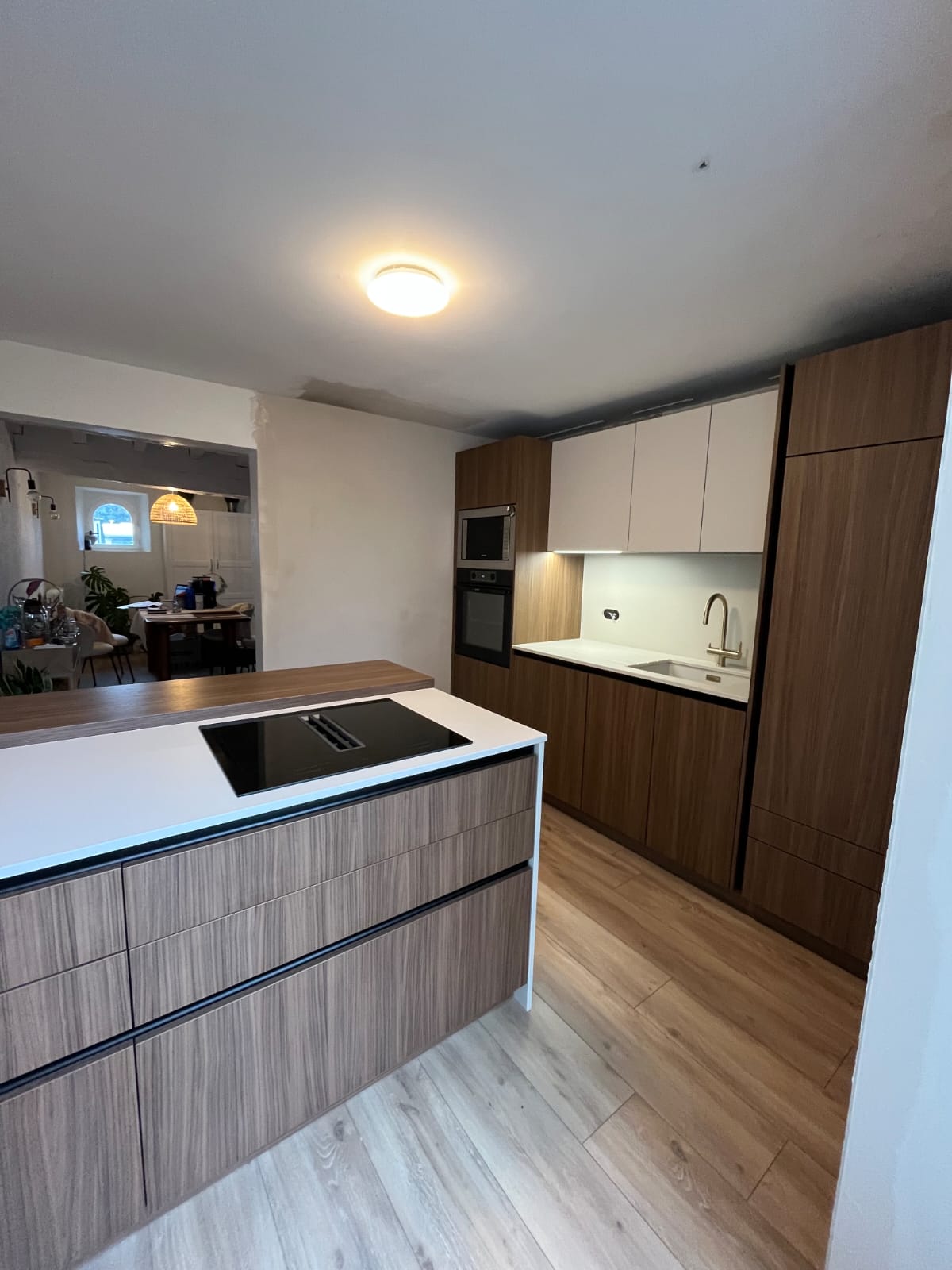 Aménagement d'une grande cuisine moderne avec îlot central vert et armoires en bois, une réalisation de NA Concept à Mauléon-Licharre.